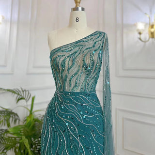 Desert Blossom: One-Shoulder Blush Pink Mermaid Evening Gown with Cape, Accented in Dubai-Inspired Emerald Green - A Luxurious Ensemble for Weddings and Grand Parties.