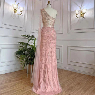 Desert Blossom: One-Shoulder Blush Pink Mermaid Evening Gown with Cape, Accented in Dubai-Inspired Emerald Green - A Luxurious Ensemble for Weddings and Grand Parties.