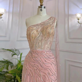 Desert Blossom: One-Shoulder Blush Pink Mermaid Evening Gown with Cape, Accented in Dubai-Inspired Emerald Green - A Luxurious Ensemble for Weddings and Grand Parties.