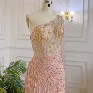 Desert Blossom: One-Shoulder Blush Pink Mermaid Evening Gown with Cape, Accented in Dubai-Inspired Emerald Green - A Luxurious Ensemble for Weddings and Grand Parties.