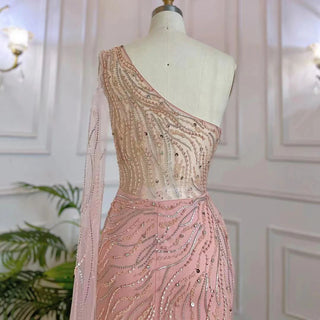 Desert Blossom: One-Shoulder Blush Pink Mermaid Evening Gown with Cape, Accented in Dubai-Inspired Emerald Green - A Luxurious Ensemble for Weddings and Grand Parties.